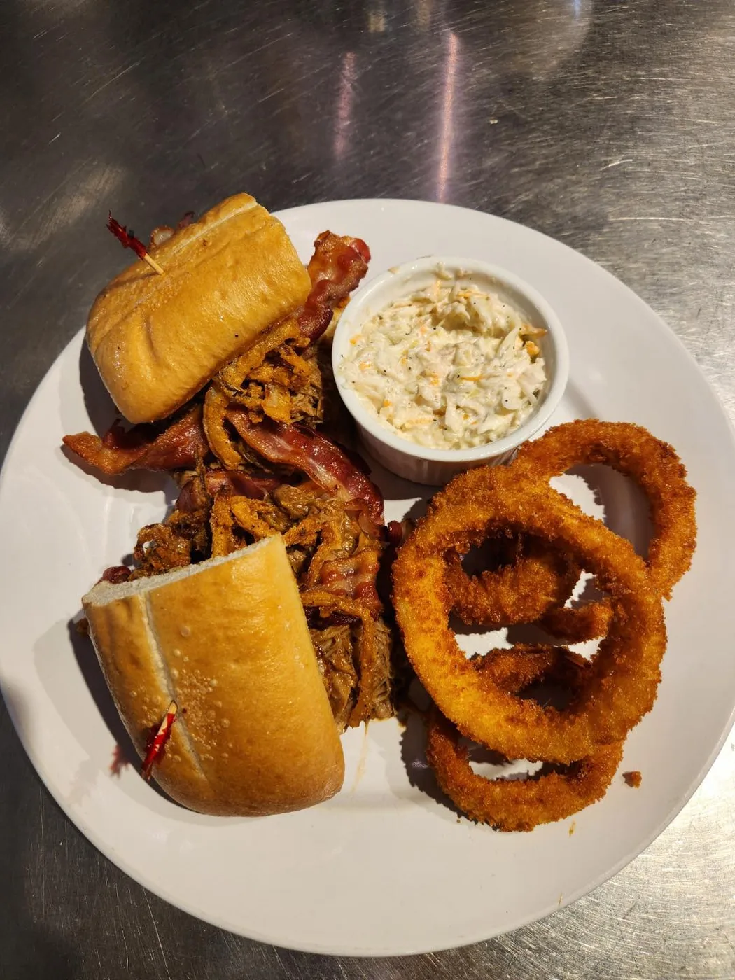 Pulled pork sandwich with onion rings and slaw